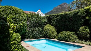 A rectangular swimming pool with a tiled edge, surrounded by well-maintained hedges and grass. - 5 Camp Street Guesthouse & Self-catering (Cape Town)