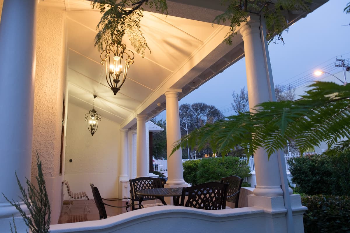 A covered porch with a table and chairs, columns, and a hanging light fixture.