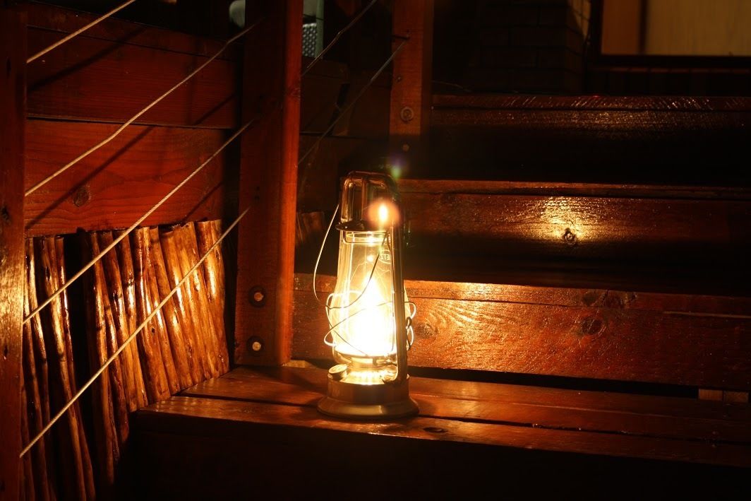 Un farol sobre un banco de madera en una habitación con poca luz.