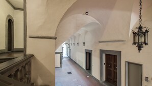 A corridor with arched ceilings, a wooden door, and a hanging lantern.