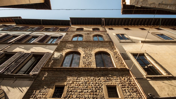 A multi-story building with stone facade, arched windows, and a flat roof.