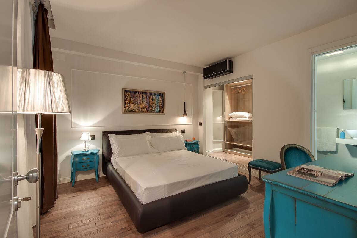 Ein modernes Schlafzimmer mit einem großen Bett, einem Nachttisch, einer Kommode, einem Spiegel und einem begehbaren Kleiderschrank.