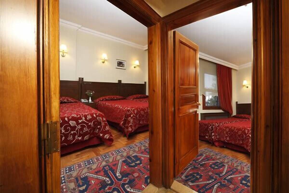 A hotel room with two beds, a wooden door, and a patterned rug.