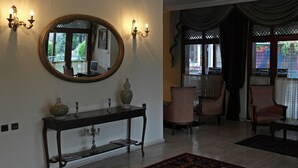 A room with a large mirror, a console table with decorative items, and two upholstered chairs. - Turquhouse Boutique Hotel (Eyup)