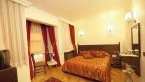 A hotel room with a large bed, a desk, a chair, a television, and a nightstand with a lamp. - Turquhouse Boutique Hotel (Eyup)