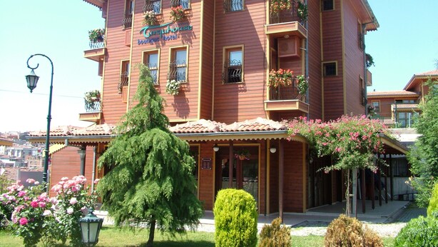 A multi-story hotel with balconies, a sign reading "Curquhuset Boutique Hotel," and a well-maintained garden with flowers and trees. - Turquhouse Boutique Hotel (Eyup)