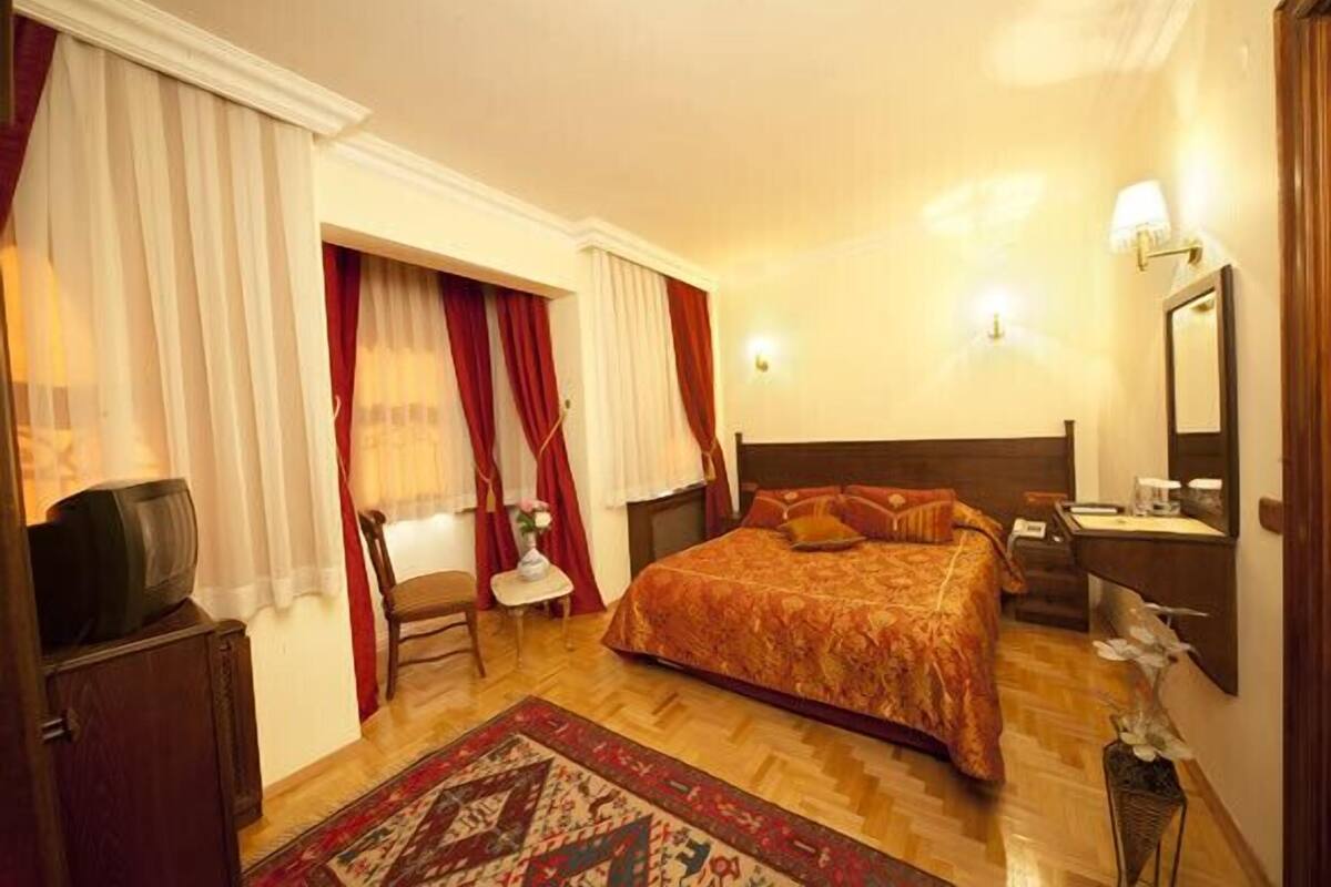 A hotel room with a large bed, a television, a desk, and a chair.