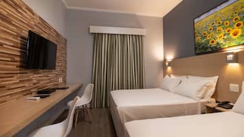 A hotel room with a wooden wall, a flat-screen TV, two beds, a desk with a chair, and a painting of sunflowers.