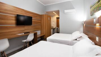 Habitació d'hotel amb una paret decorativa de fusta, televisió de pantalla plana, dos llits, escriptori amb cadira i bany visible a través d'una porta oberta.