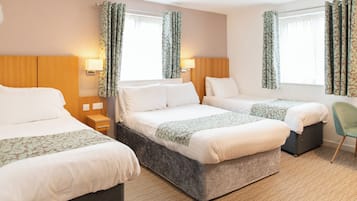A hotel room with two beds, a bedside table, a chair, and a window with curtains.