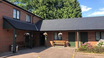 A brick building with a reception area, a wheelchair-accessible parking space, and hanging flower baskets.