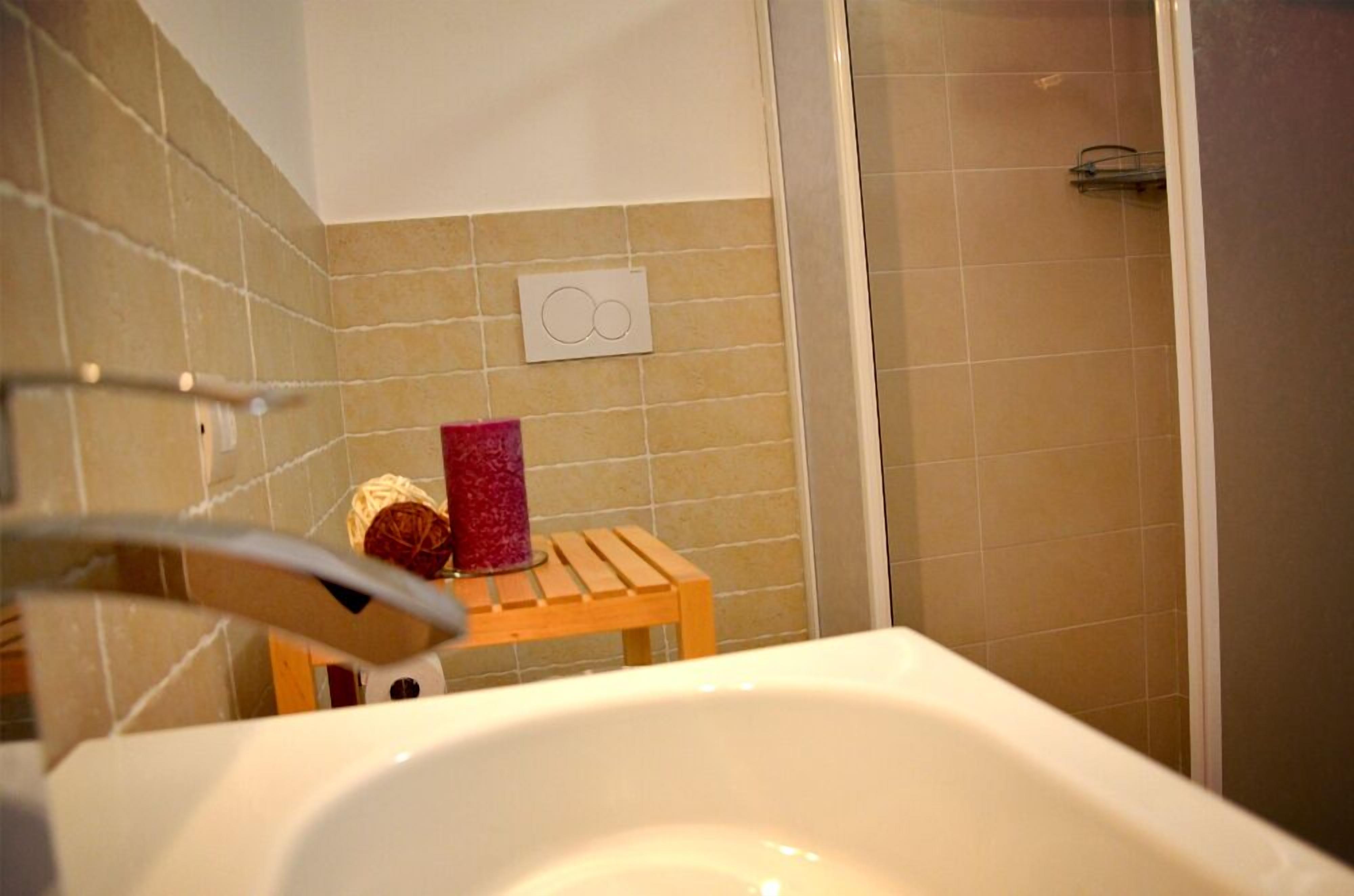 Un baño con bañera, un taburete de madera y zona de ducha.