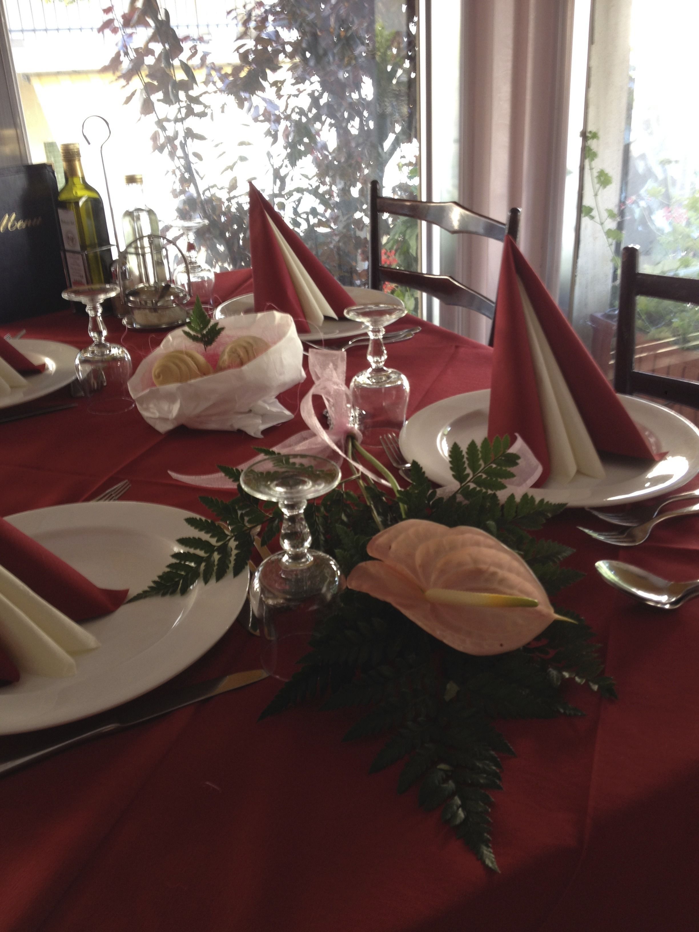 A table set for a meal with red napkins, white plates, and a glass wine bottle.