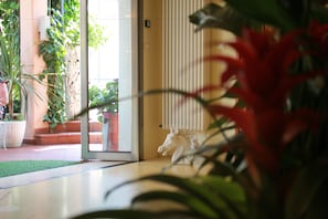 Un intérieur moderne avec une porte vitrée donnant sur un patio, une statue de cheval blanc et diverses plantes en pot.