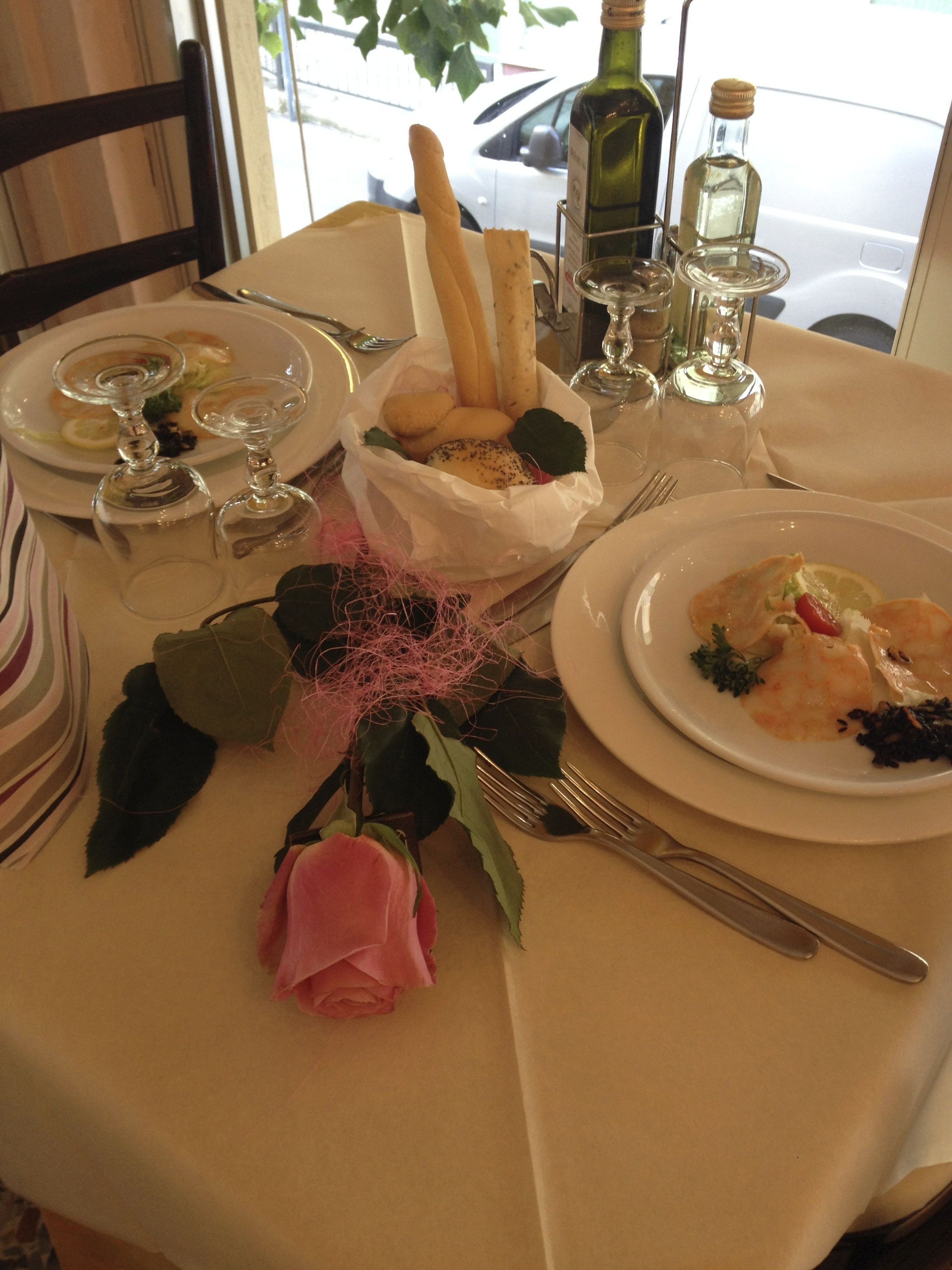 Une table mise pour un repas, avec des assiettes remplies de nourriture, des verres à vin et un bouquet de fleurs.