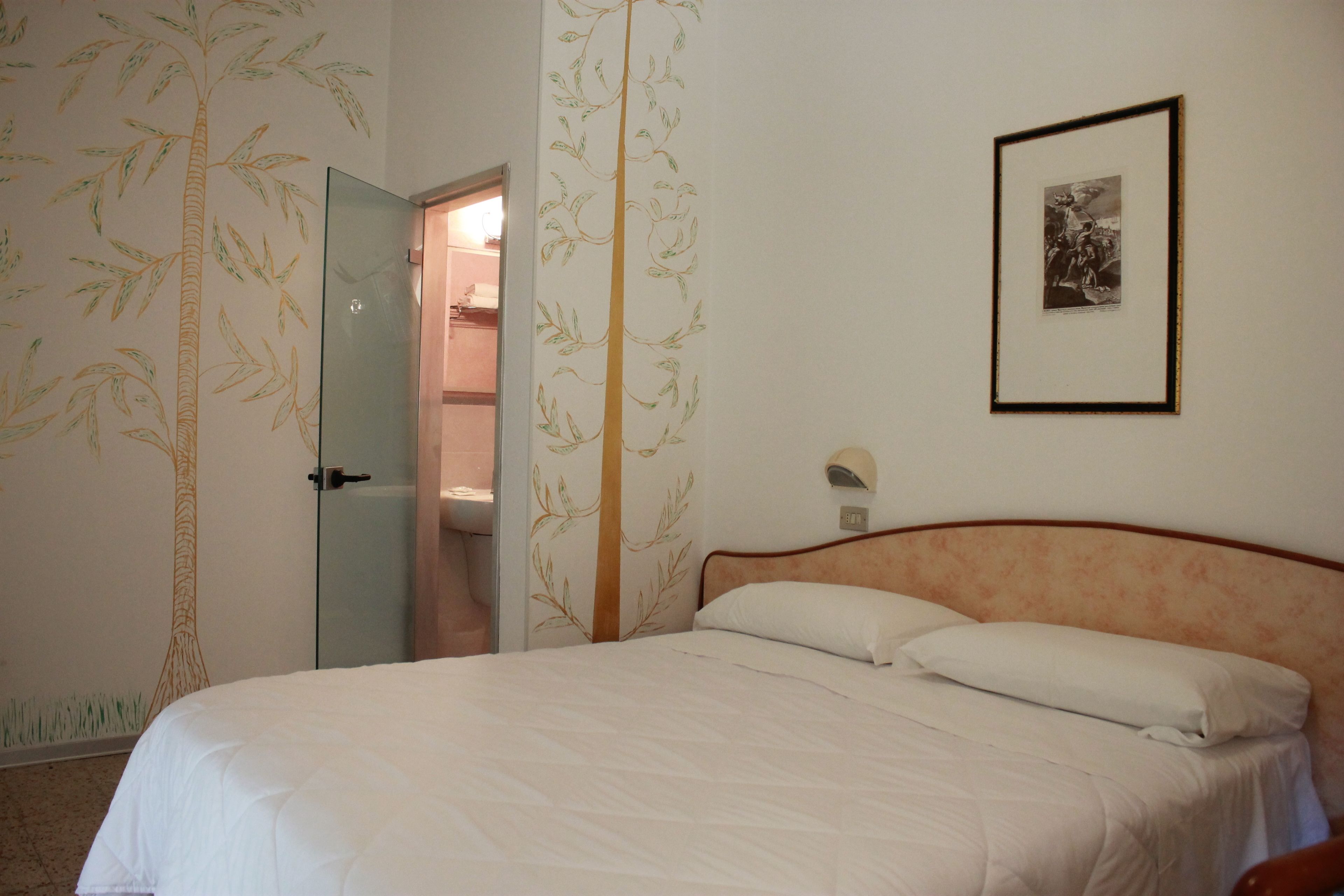 Ein Schlafzimmer mit einem Bett, einer Tür zu einem Badezimmer und einem gerahmten Bild an der Wand.