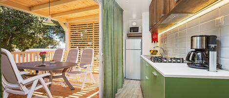A kitchen with a green island, white cabinets, and a dining area with a table and chairs.