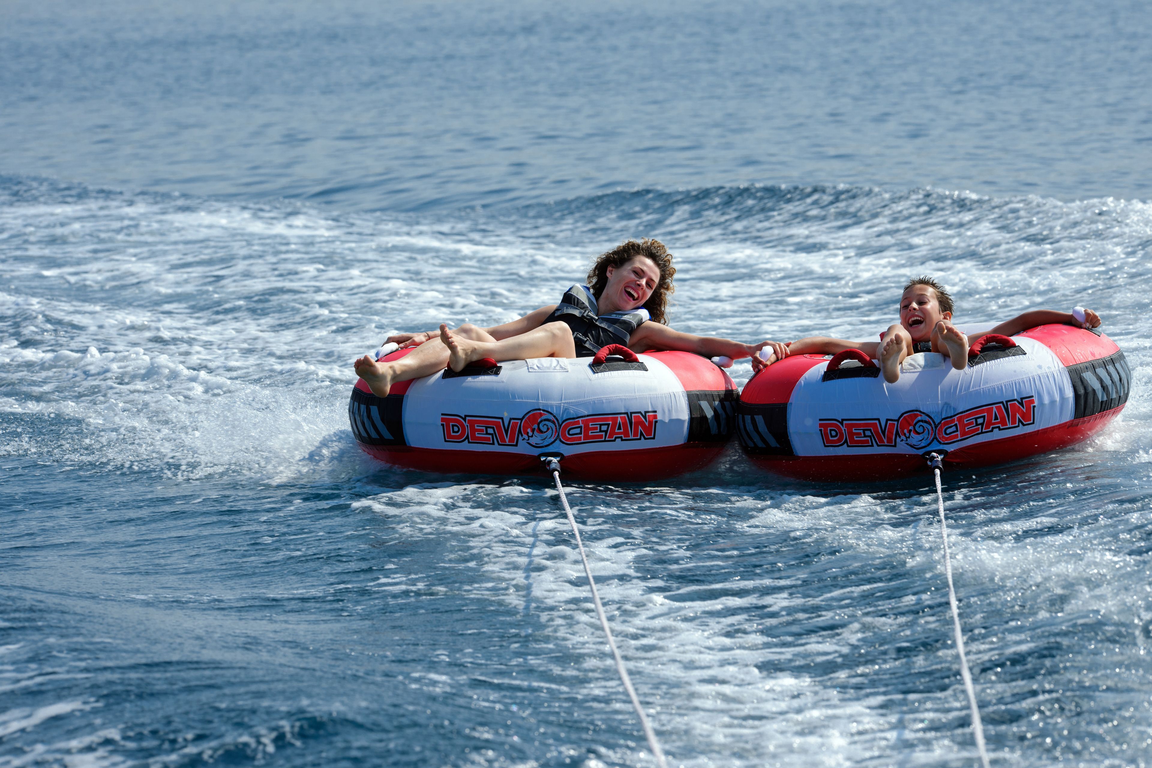 Two people on water tubes with 'DEVOCEAN' branding, floating on a body of water.