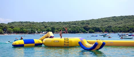 Parque acuático con toboganes inflables y una playa al fondo.