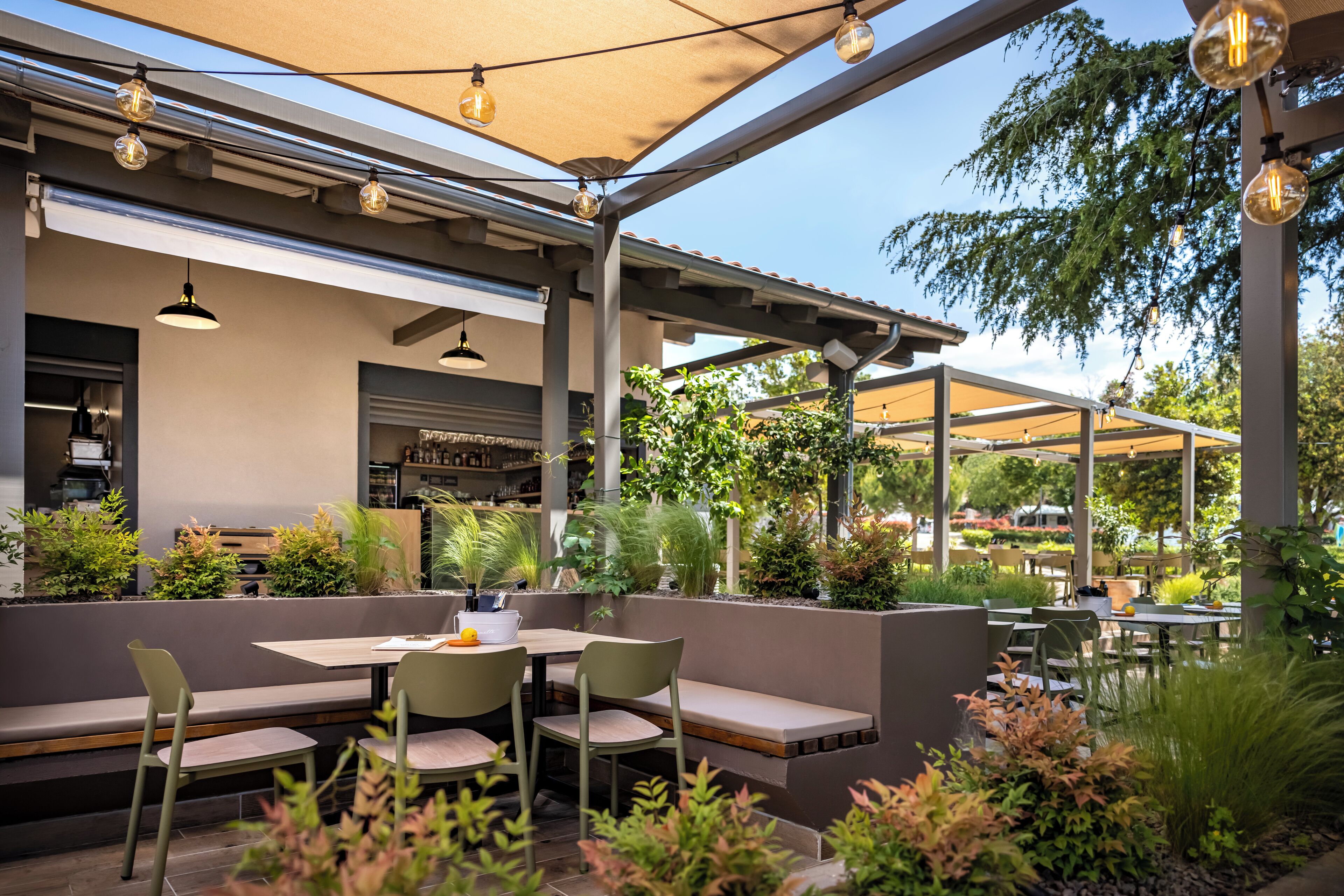 Un espace extérieur aménagé en terrasse, avec des sièges, des tables et des guirlandes lumineuses.