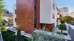 A modern building with a wooden facade and white walls, surrounded by greenery and other residential buildings. - Residence by Vestibul Palace (Split)