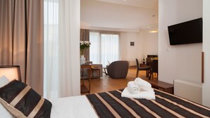 A hotel room with a bed, a desk, a chair, a TV, and a view of the dining area. - Residence by Vestibul Palace (Split)