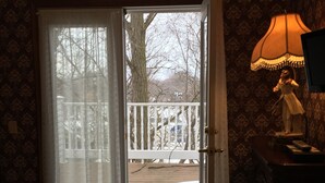 A room with a bed, a lamp, and a view of a snowy deck through a glass door.