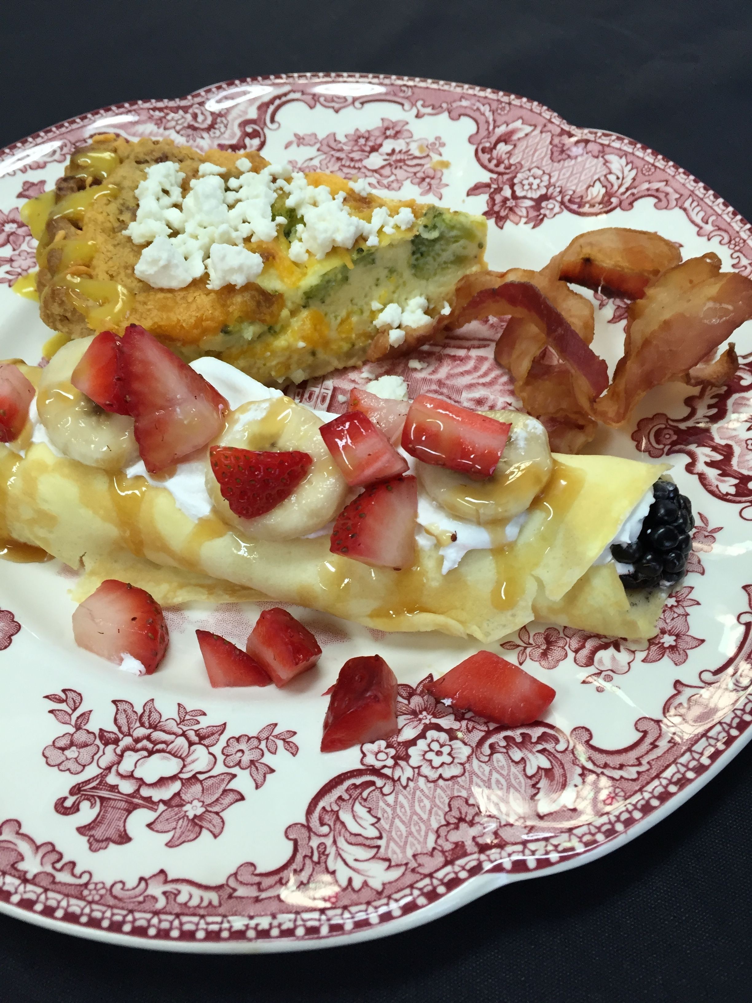 A plate with a variety of breakfast items including pancakes, bacon, and fruit.