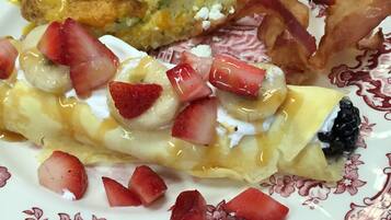 A plate with a variety of breakfast items including pancakes, bacon, and fruit.