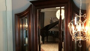A dining area with a wooden sideboard, a chandelier, and a piano in the background. - Ginkgo Tree Inn (Mount Pleasant)