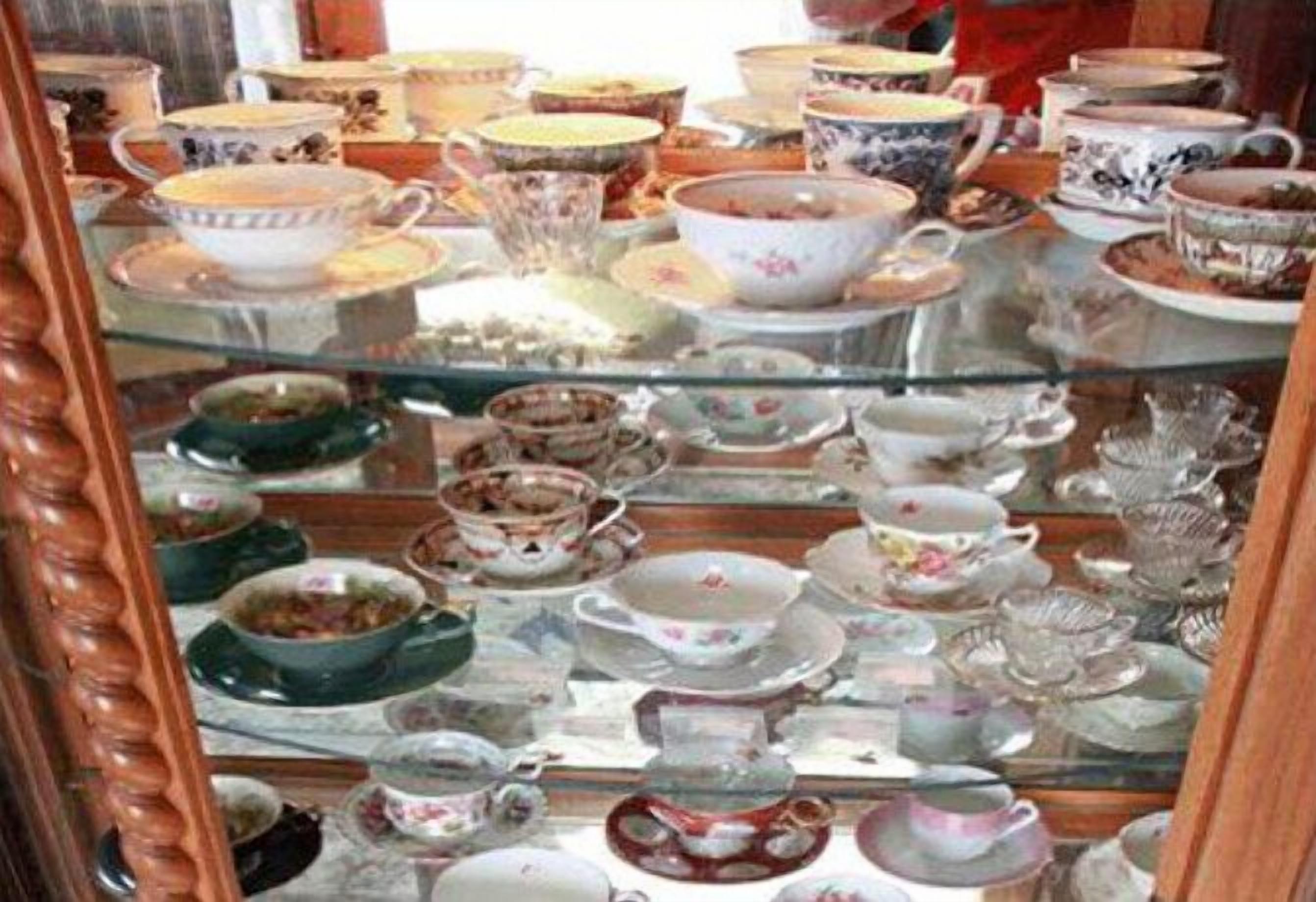 A glass display case filled with various ceramic tea sets and teapots.