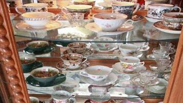 A glass display case filled with various ceramic tea sets and teapots.