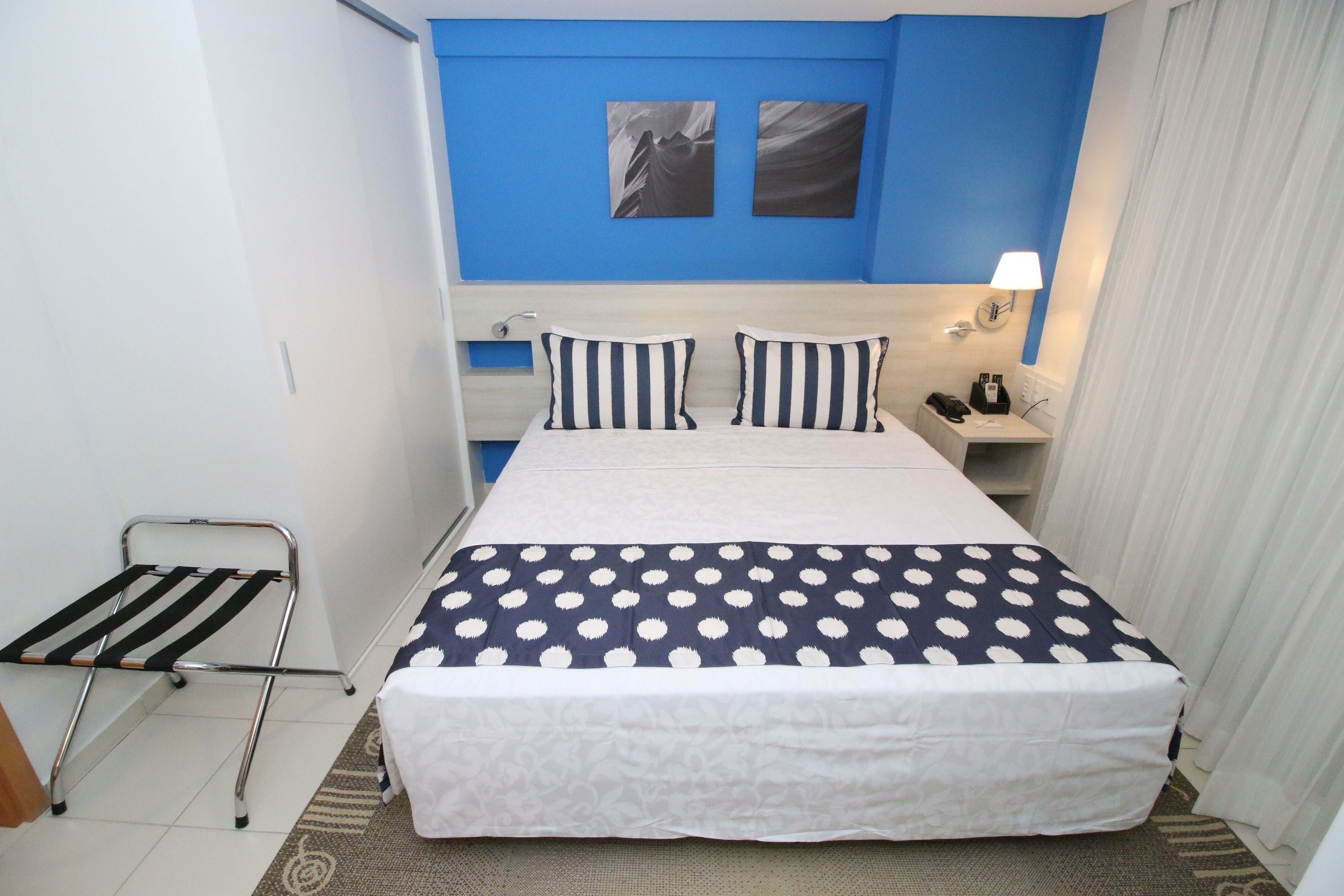 Une chambre d’hôtel avec un lit, une table de chevet, une lampe et une œuvre d’art au mur.