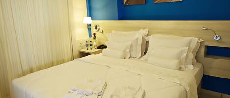 Een hotelkamer met een groot bed, twee nachtkastjes, een lamp en kunst aan de muur.