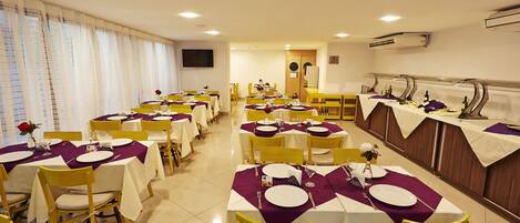 Comedor con varias mesas dispuestas para comidas, sillas y un mostrador tipo bufé.