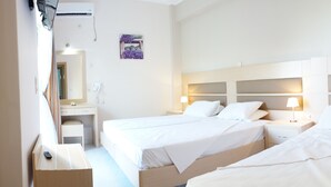 Een hotelkamer met twee éénpersoonsbedden, een bureau met stoel, een spiegel en een airconditioning.