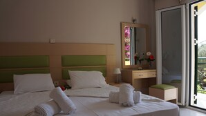 Een hotelkamer met een groot bed, een nachtkastje, een spiegel en uitzicht op de omgeving.