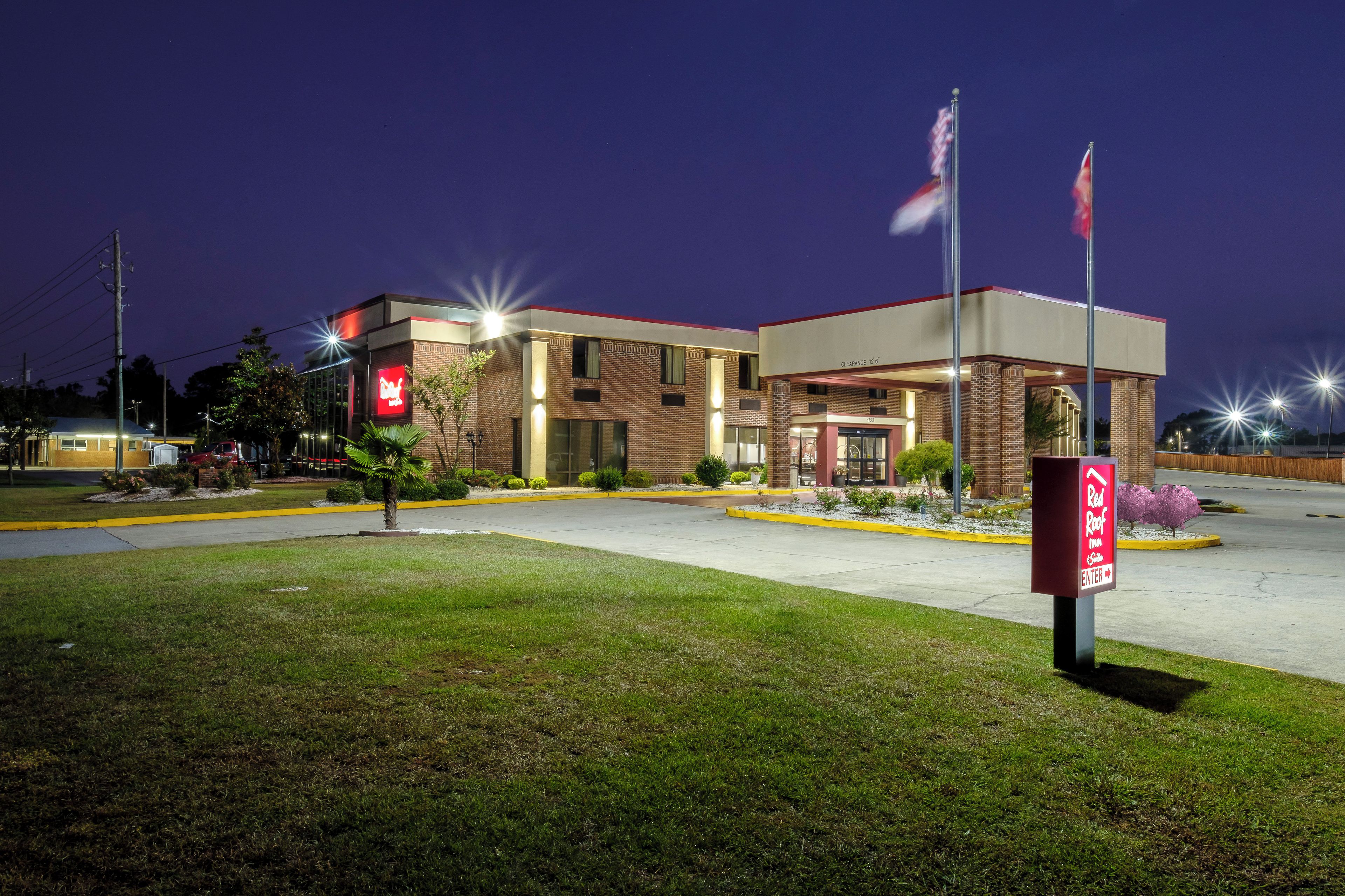 A building with a red sign, a parking lot, and a flagpole.