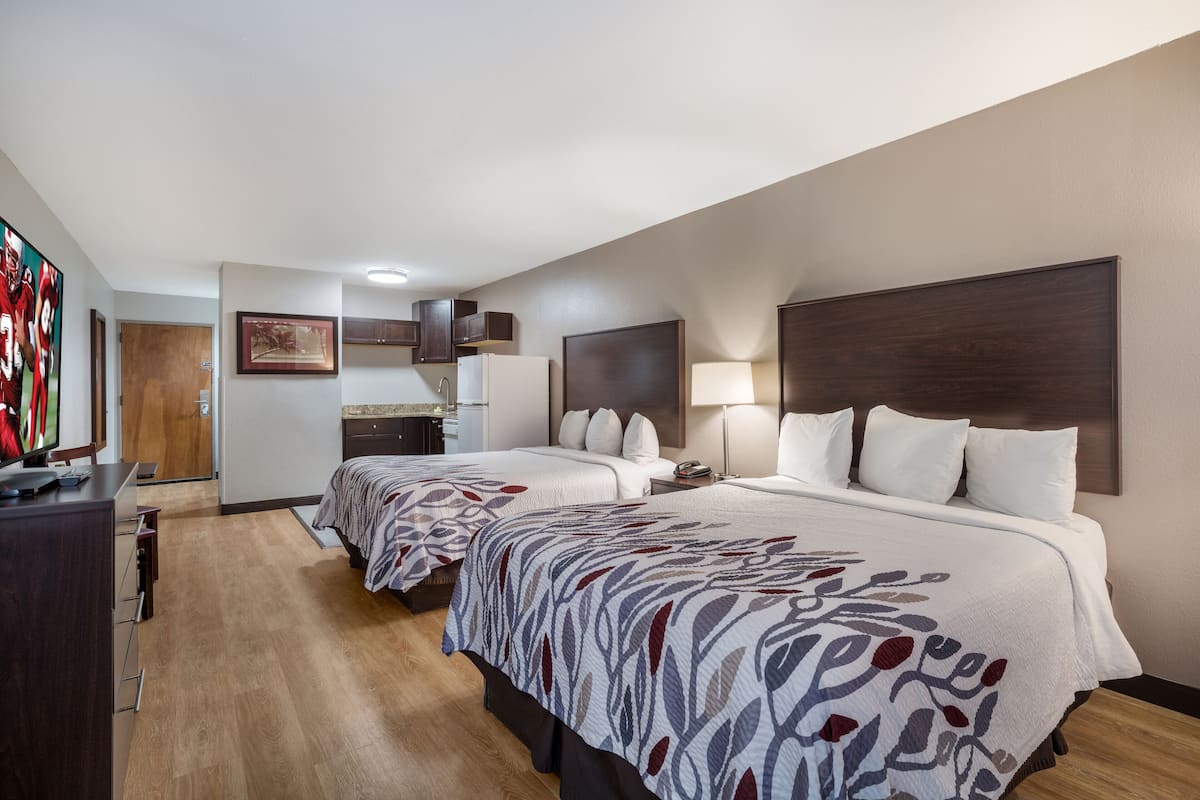 Une chambre d’hôtel avec deux lits, un bureau, une télévision et une salle de bain.