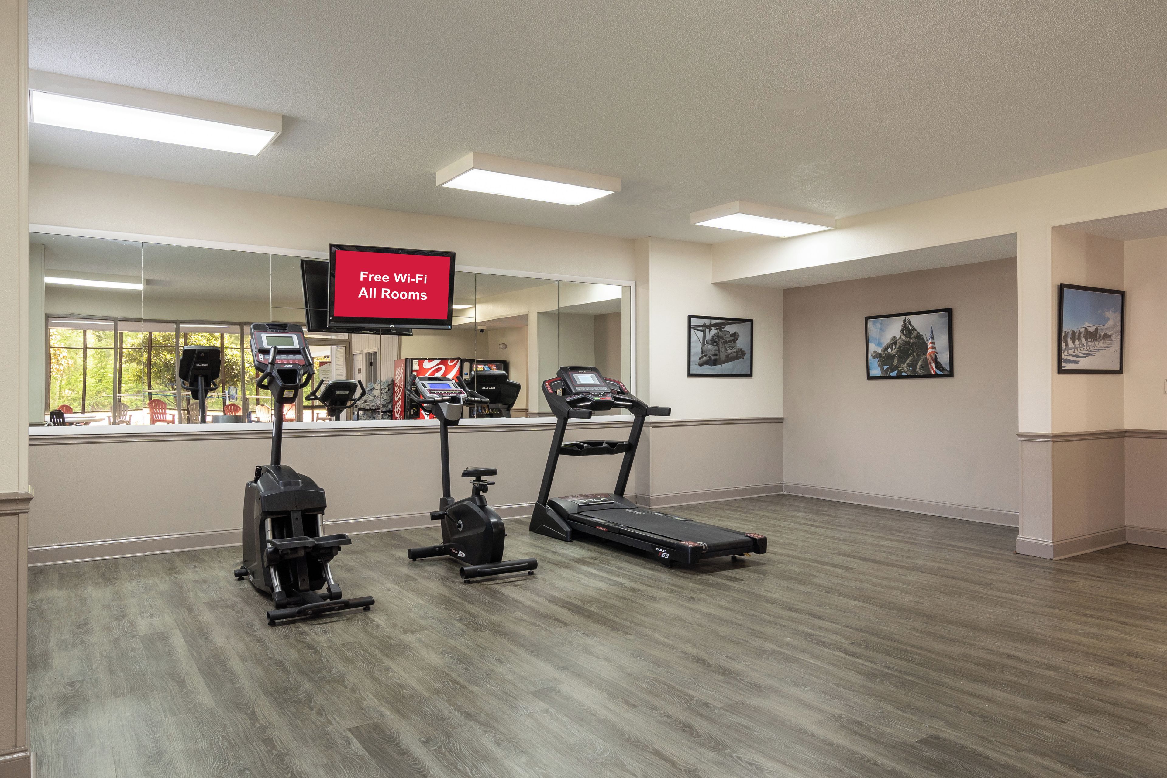 A fitness center with treadmills, stationary bikes, and a TV screen advertising free Wi-Fi.