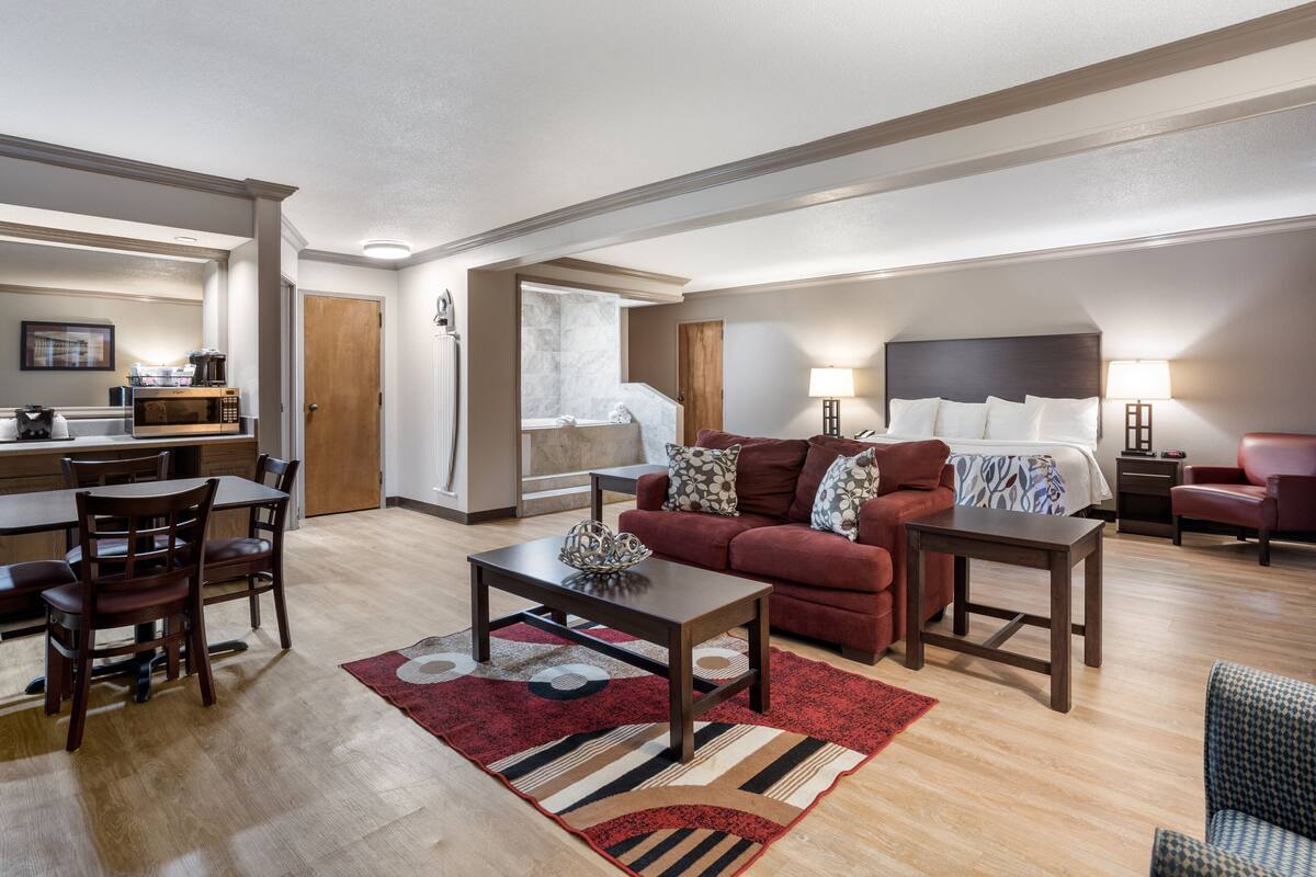 Un salon moderne comprenant un coin repas, un ensemble de canapés, une table basse et un tapis rouge.