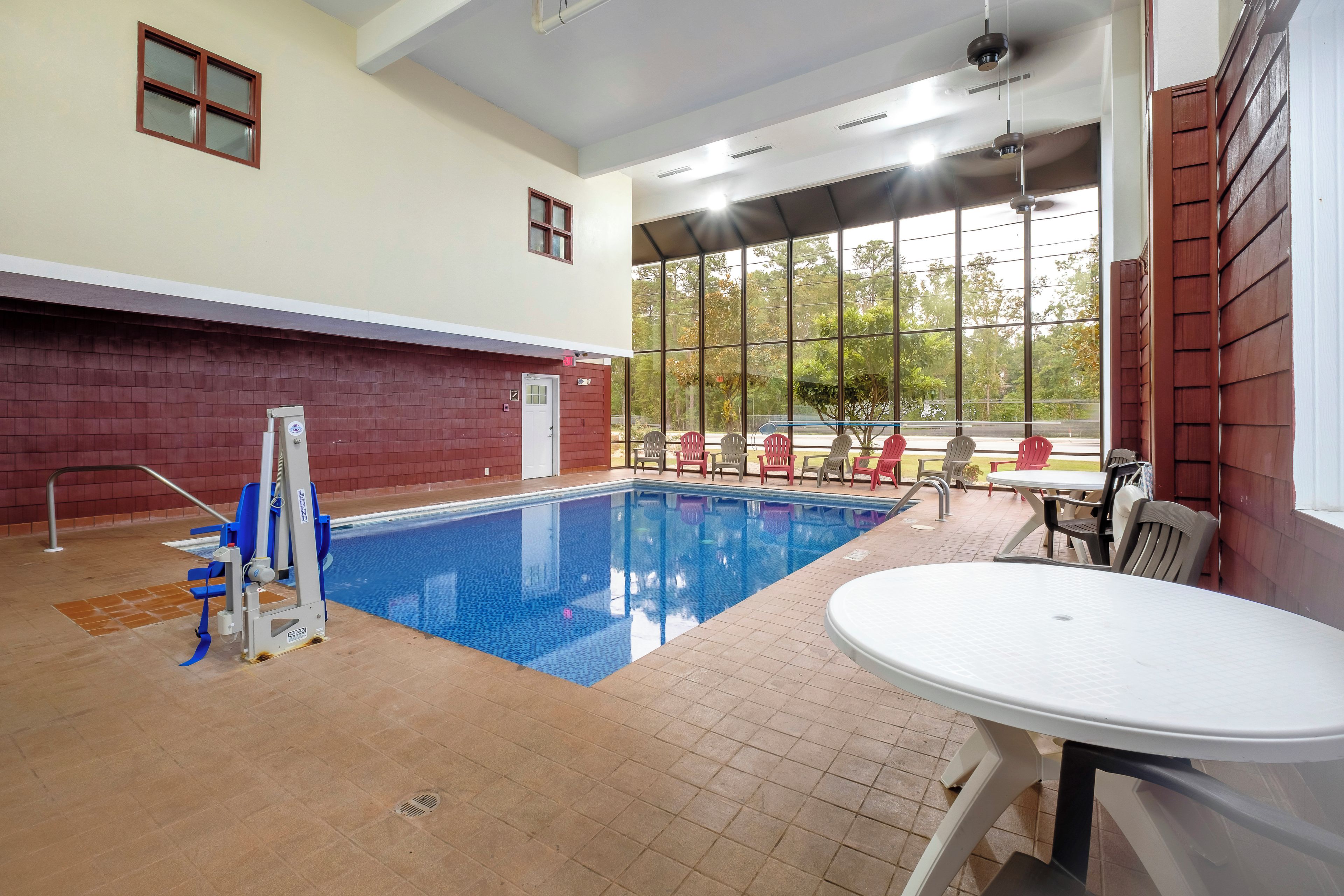 An indoor swimming pool with a lifeguard chair, a table, and chairs near the pool.