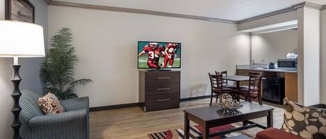 A living room with a flat-screen TV, a dining area, and a kitchen.