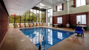 An indoor swimming pool with clear glass walls, a tiled floor, and several lounge chairs around the pool. - Red Roof Inn & Suites Jacksonville, NC (Jacksonville)