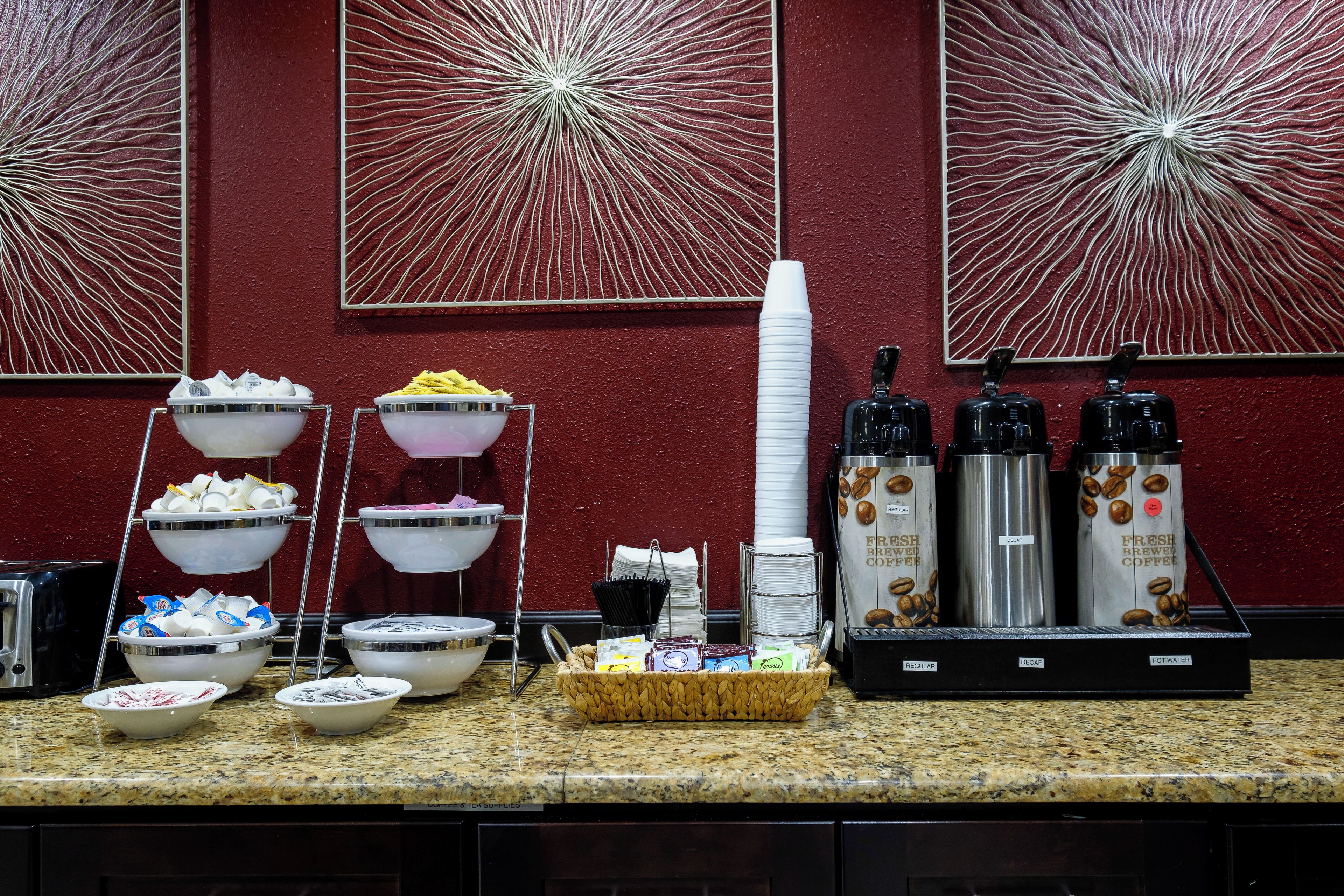 A buffet setup with various food and beverage dispensers, including coffee and tea options.