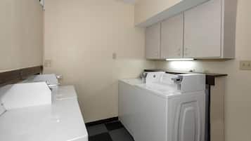 A laundry room with a washing machine and dryer, a countertop with a coffee maker, and a cabinet above the dryer.