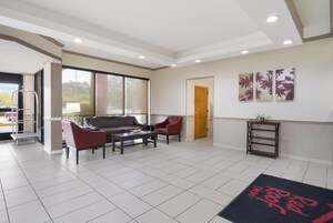 Amplia sala de estar con sofá, sillones, una mesa de centro y una mesita auxiliar. Hay una puerta corrediza de vidrio que da a un área exterior, y una puerta a otra habitación.