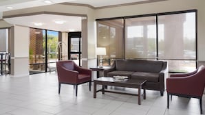 A spacious living area with a sofa, armchairs, and a coffee table. - Red Roof Inn & Suites Jacksonville, NC (Jacksonville)
