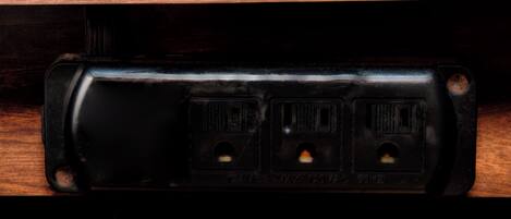 A black electrical outlet with three sockets, two of which are visible.