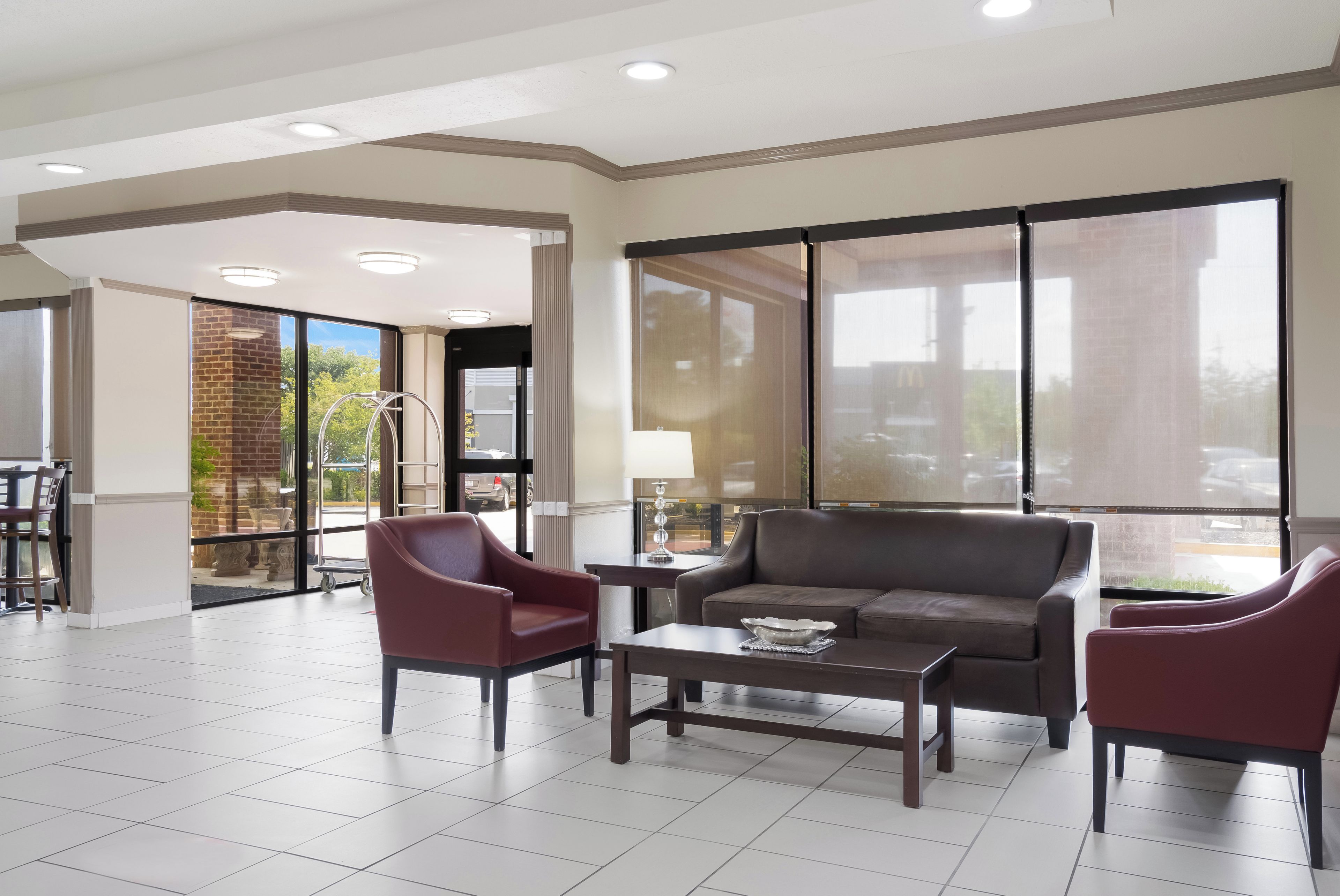 A spacious living area with a sofa, armchairs, and a coffee table. There is a large window providing a view of the outdoors.